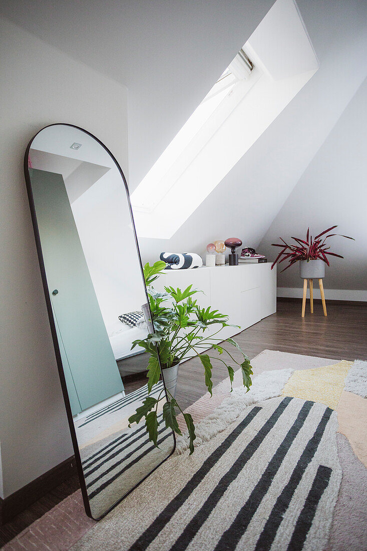 Leaning arched mirror on carpet with graphic design in an attic room