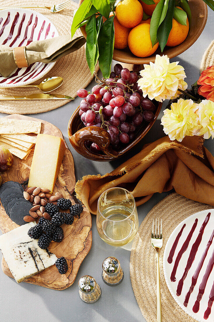 Gedeckter Tisch mit Käse, Obst und Weißwein