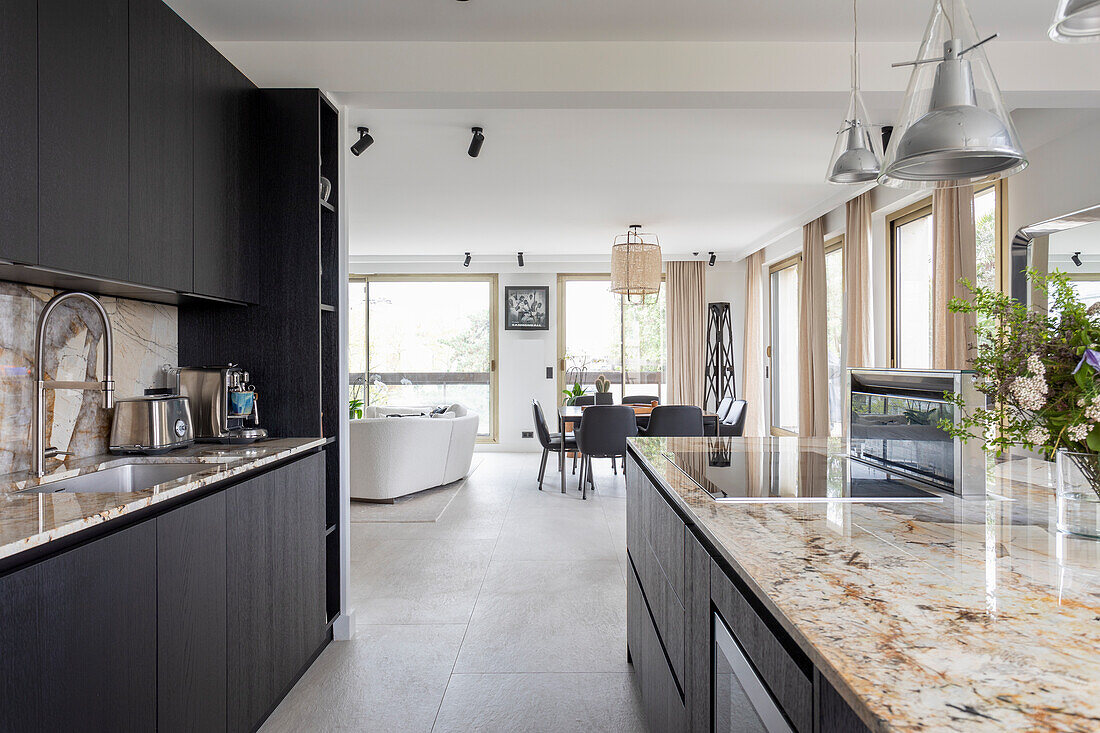 Elegante Küche mit schwarzen Schrankfronten und Granit-Arbeitsplatte in offenem Wohnraum