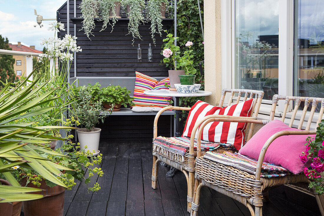 Wohnliche Terrasse mit Rattanstühlen, Sitzbank und Topfpflanzen