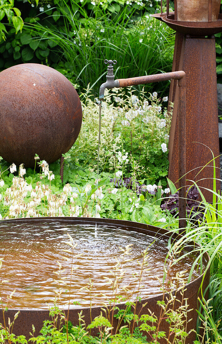 Gartenbrunnen mit rostigem Gefäß