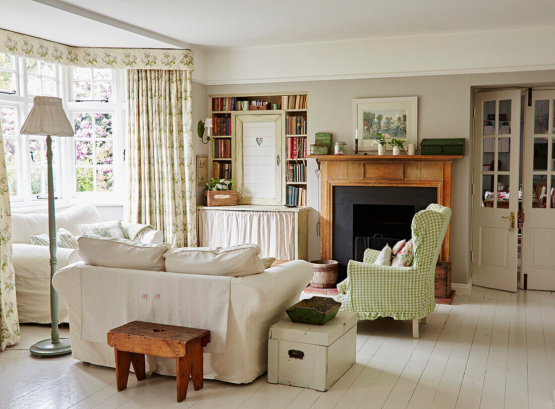 Sofas and green and white checked wing chair in the living room with bay window