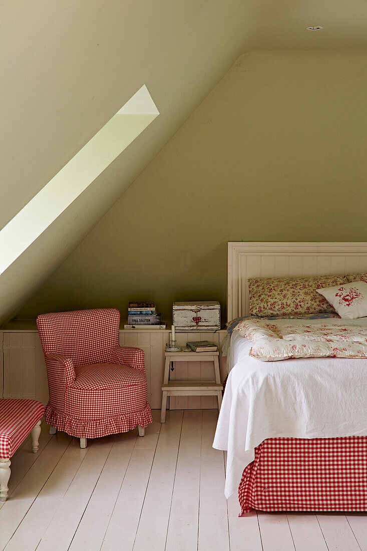 Gingham chair and bench next to bed with flowered quilt