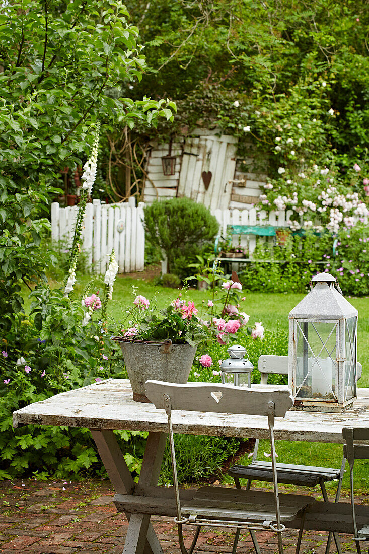 Klappstuhl am Tisch auf der Gartenterrasse mit Gartenblick