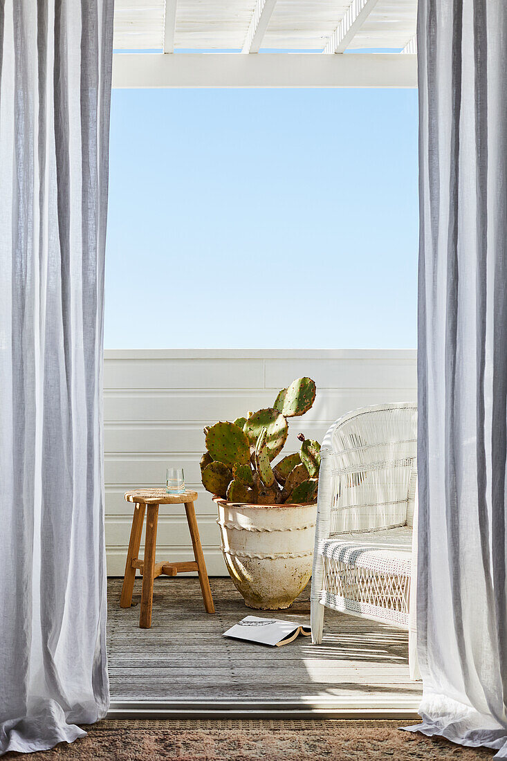 Blick auf kleinen Balkon mit Rattansessel und Kaktus