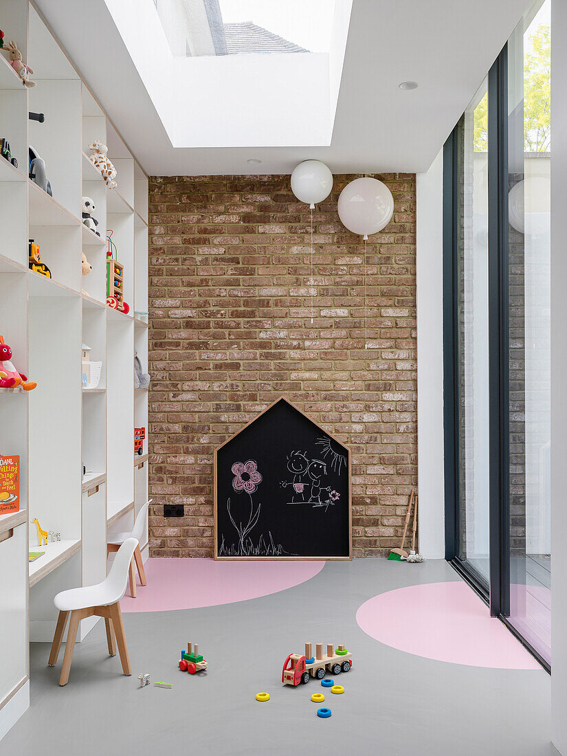 Children's playroom with floor-to-ceiling shelving, brick wall, and sliding glass door