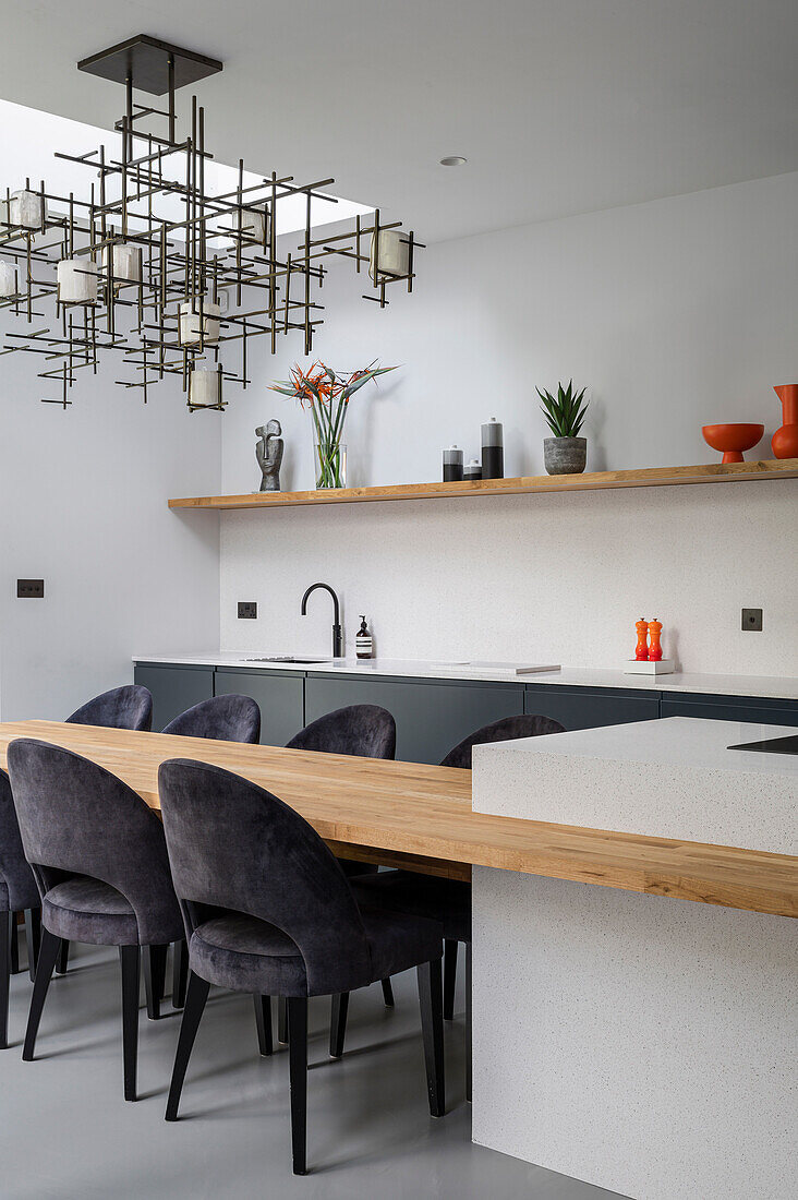 Wooden dining table extended from the kitchen island and elegant upholstered chairs