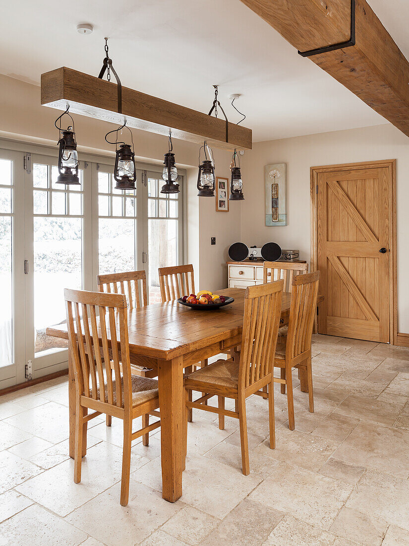 Dining area with wooden furniture, hurricane lanterns hanging from the wooden beam
