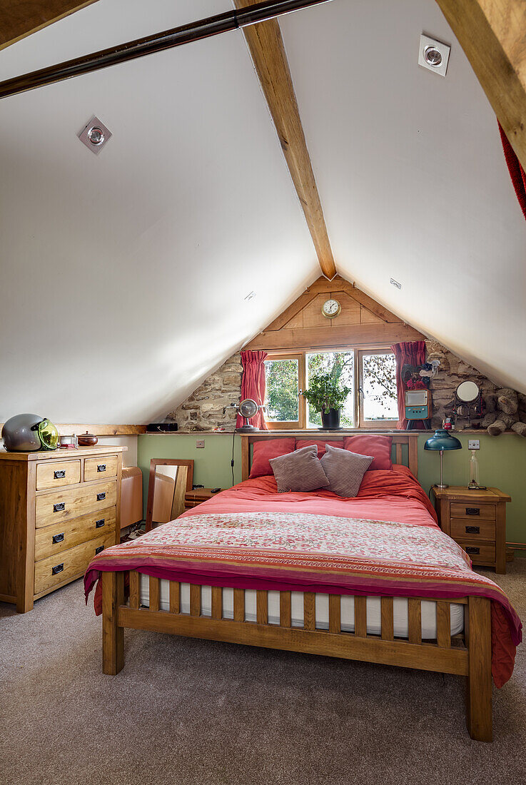 Wooden queen bed and dresser in an attic bedroom
