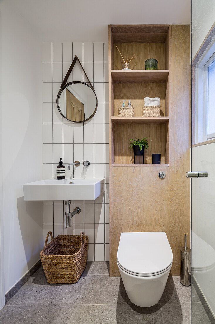wall mounted sink, toilet, and wooden shelf in the bathroom