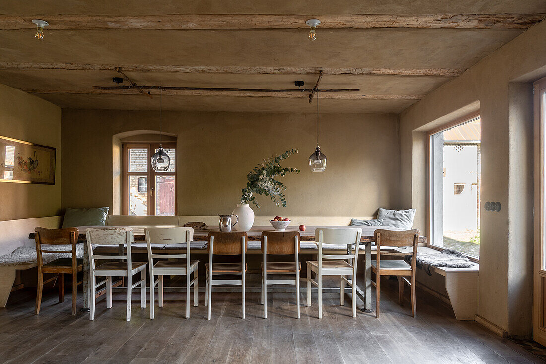 Langer Esstisch aus Holz mit Sitzbank und Stühlen in ländlichem Zimmer in Erdtönen