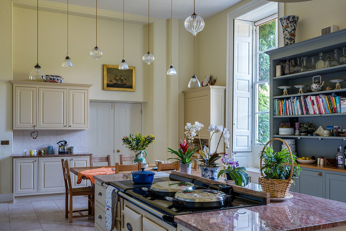 Modernisierte Landhausküche mit Kochinsel, Anrichte und Hängelampen aus Glas
