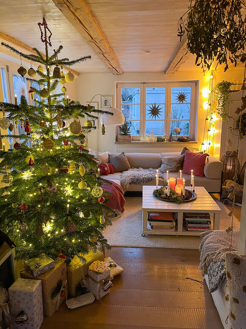 Beleuchteter Weihnachtsbaum, darunter Geschenke im Wohnzimmer