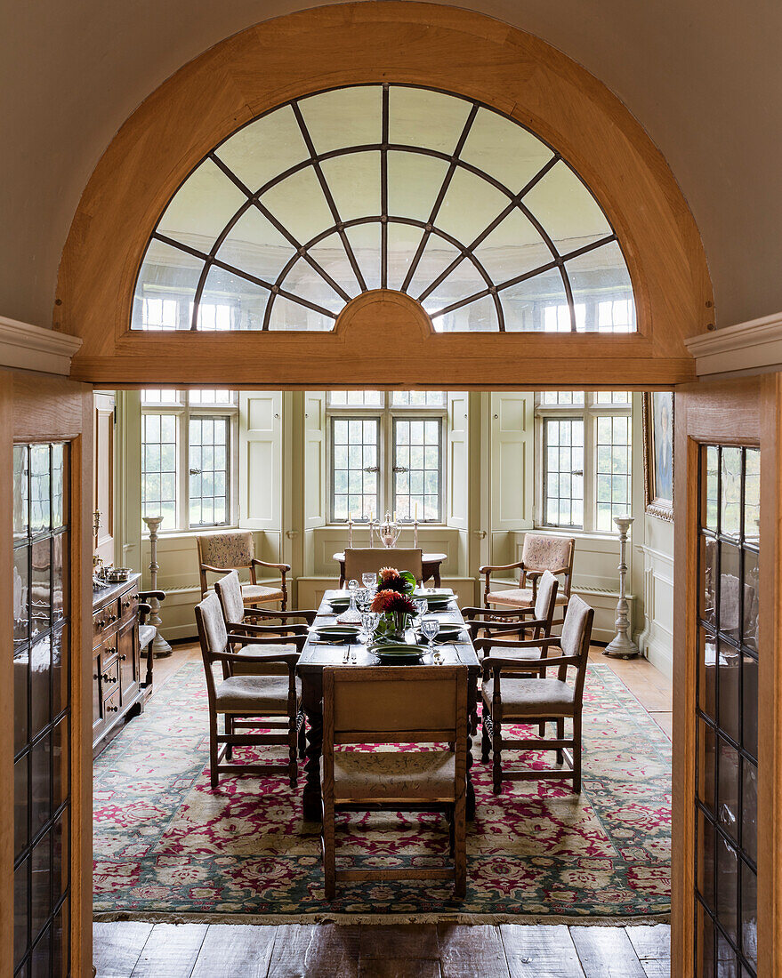 View through open double doors into dining room with antique chairs