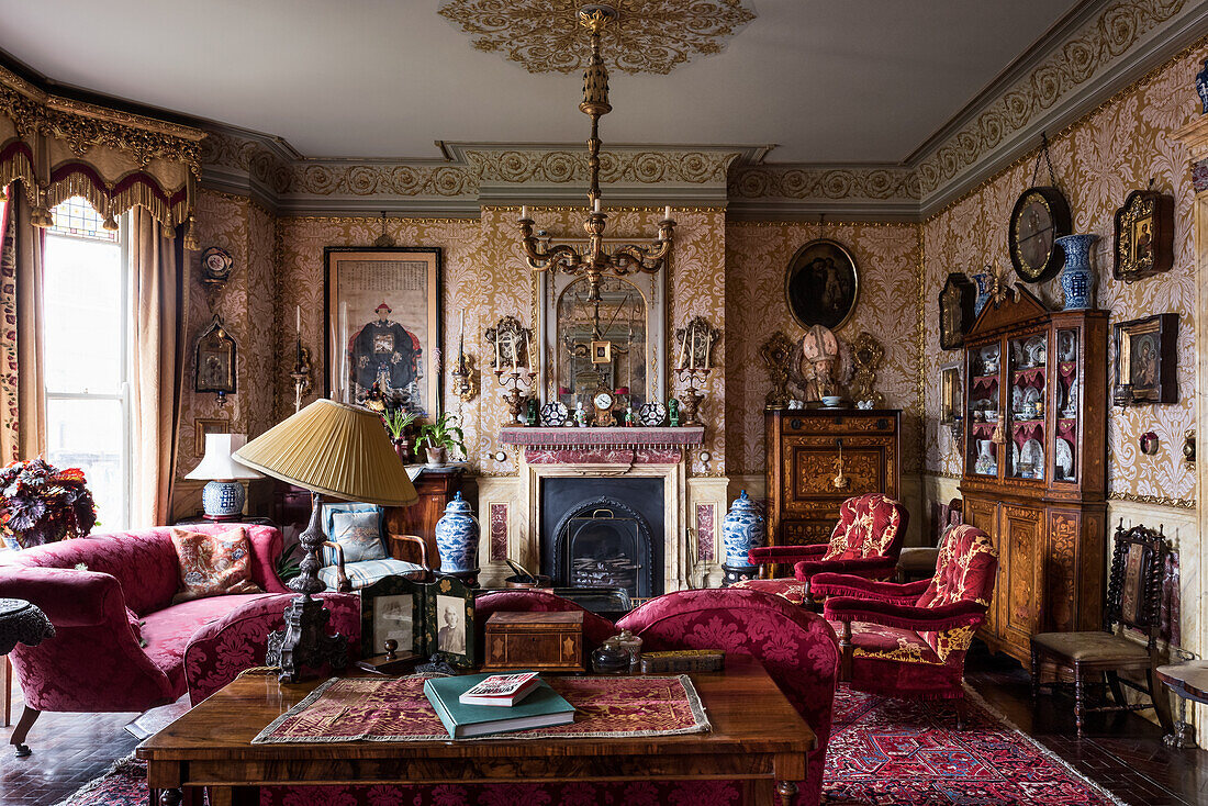 Velvet furniture and antiques in a Victorian room with ornamental wallpaper
