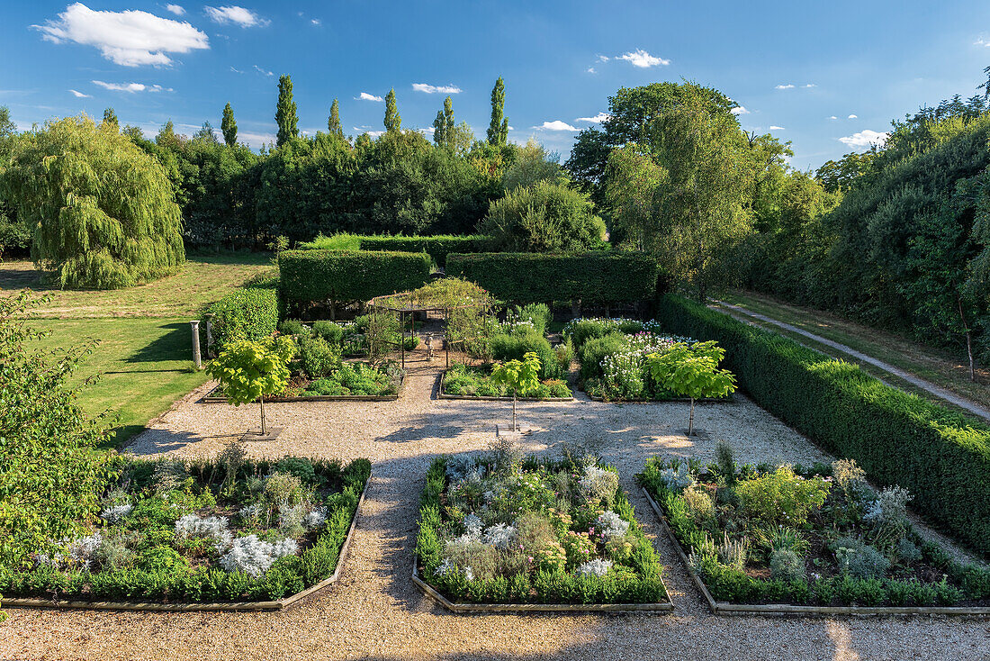 Box tree lined perennial beds in English country house garden