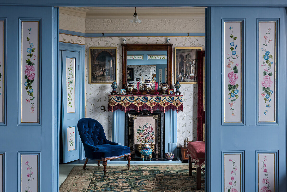Dekorative Türverkleidungen und blauer Samtsessel vor Kamin im Schlafzimmer