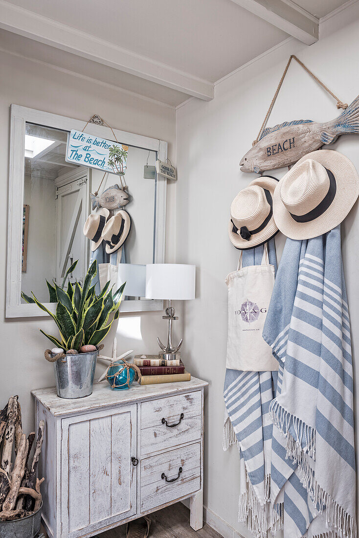 Treibholzfisch als Wandgarderobe mit Sonnenhüten und Handtüchern, Holzschränkchen und Spiegel in der Diele