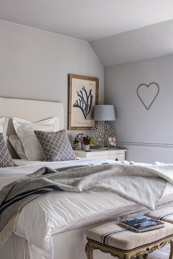 Ungemachtes Bett im Zimmer mit Herzdeko an der Wand in einem Cottage