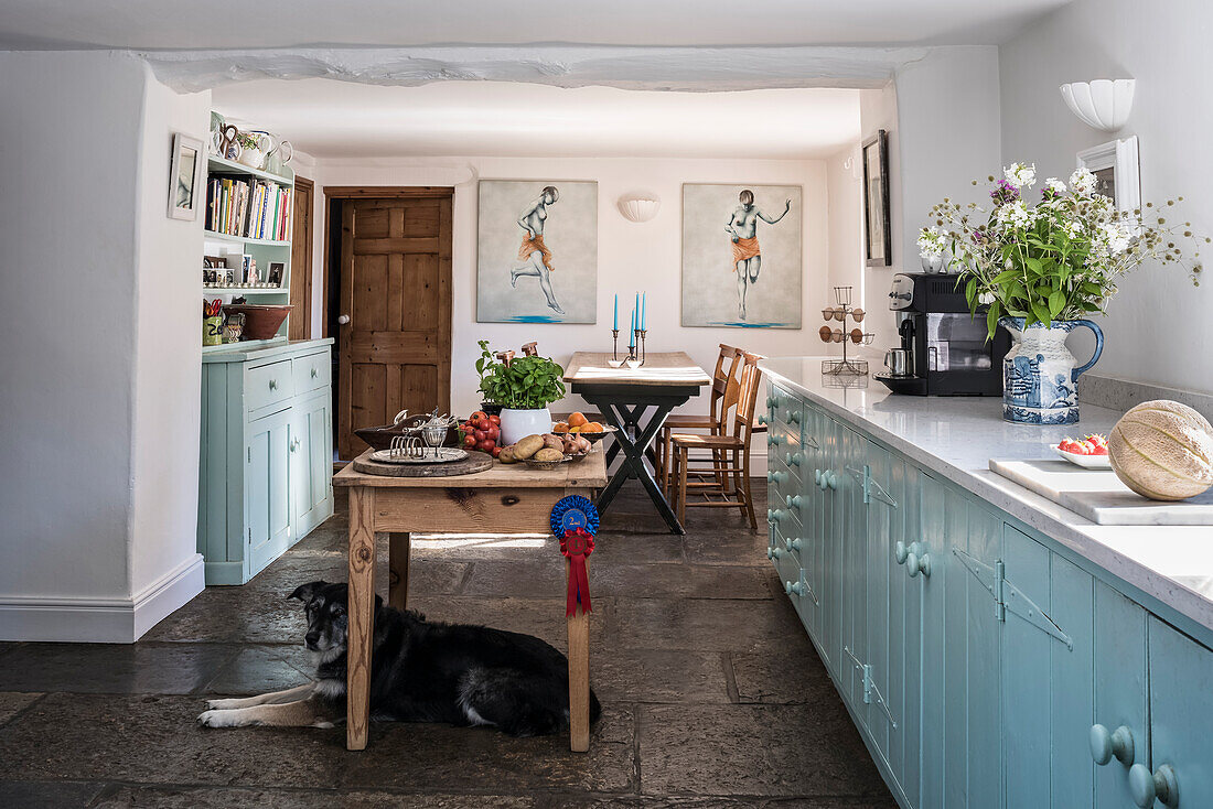Küche mit Silestone-Arbeitsflächen, hellblauen Schrankfronten und Steinplattenboden in renoviertem Bauernhaus