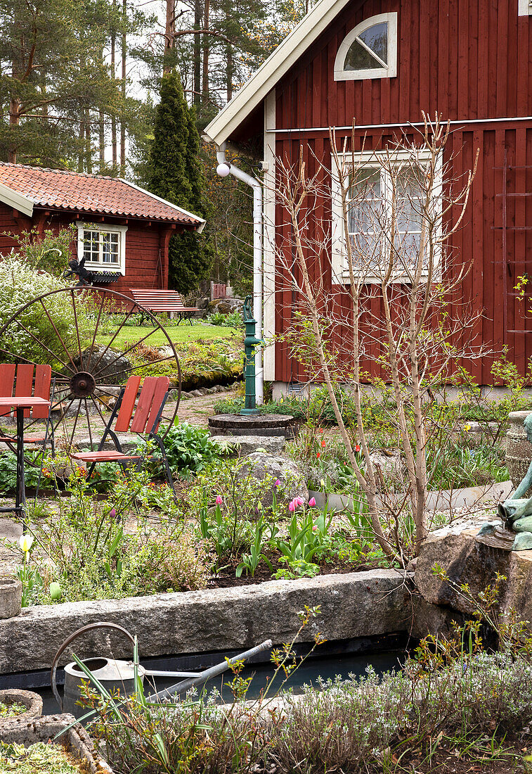 Teich im Bauerngarten, im Hintergrund rotbraunes Holzhaus