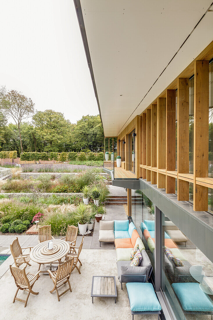 Terrace with sofa and dining table at the architect's house with a large garden