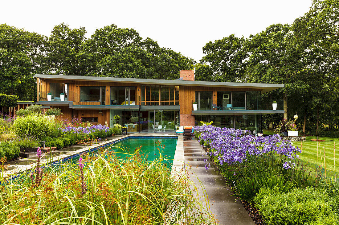 Blumenbeete um den Pool im Garten um luxuriöses Architektenhaus