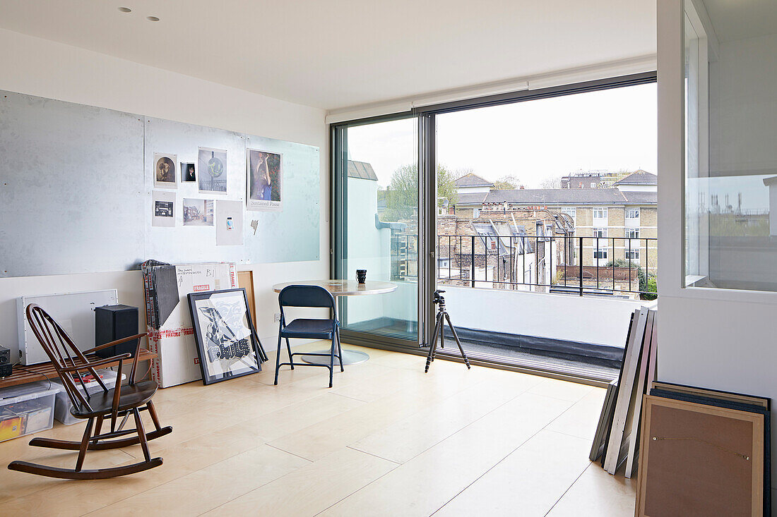 Schaukelstuhl und Bilder im minimalistischen Atelier mit großem Balkon
