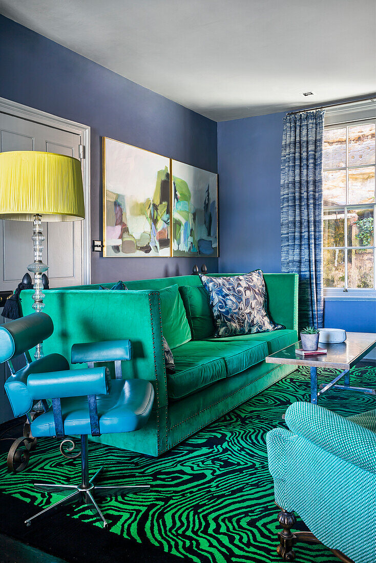 Green sofa, vintage leather chair and carpet with malachite pattern in the living room with blue walls