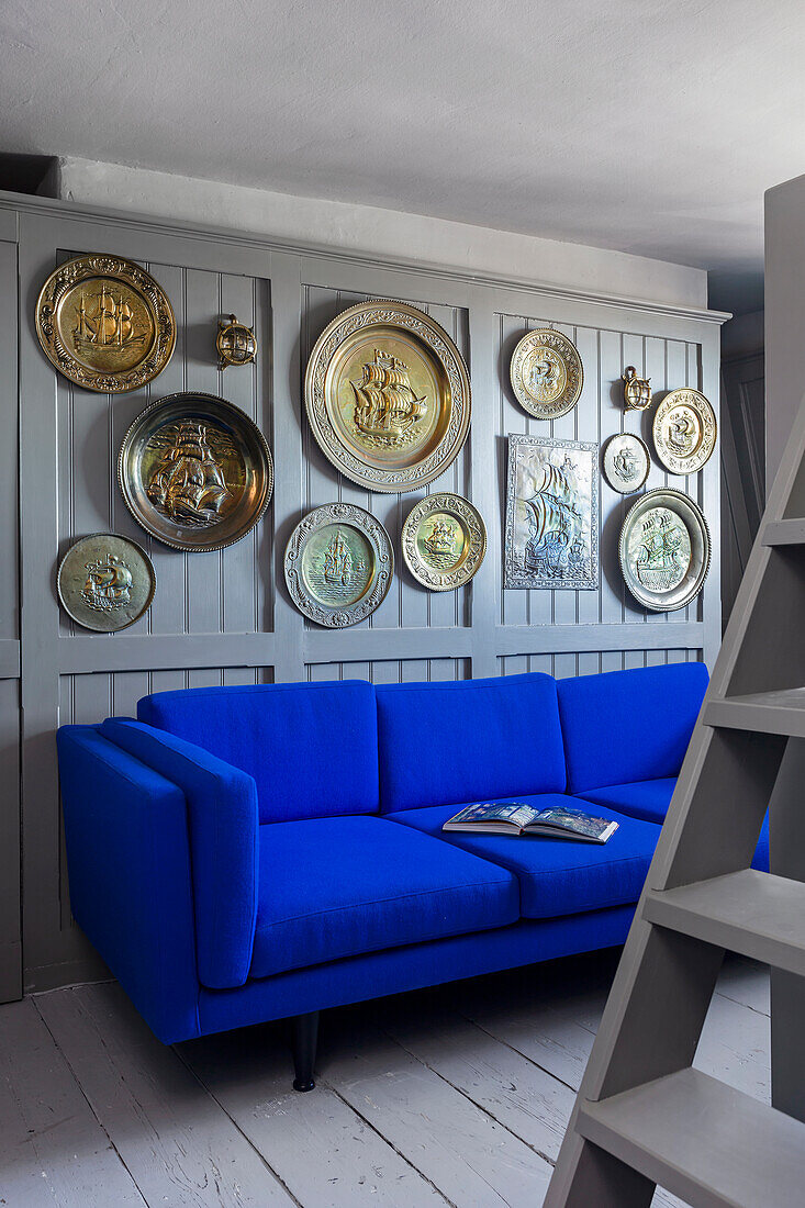 Blue sofa, above it wall mounted plate collection