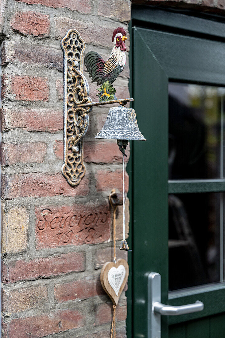 Bell with rooster design on a brick wall