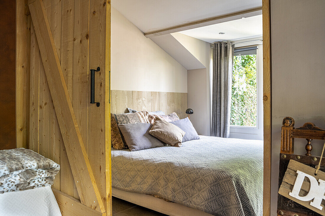 View through open wooden sliding door looking toward a queen sized bed