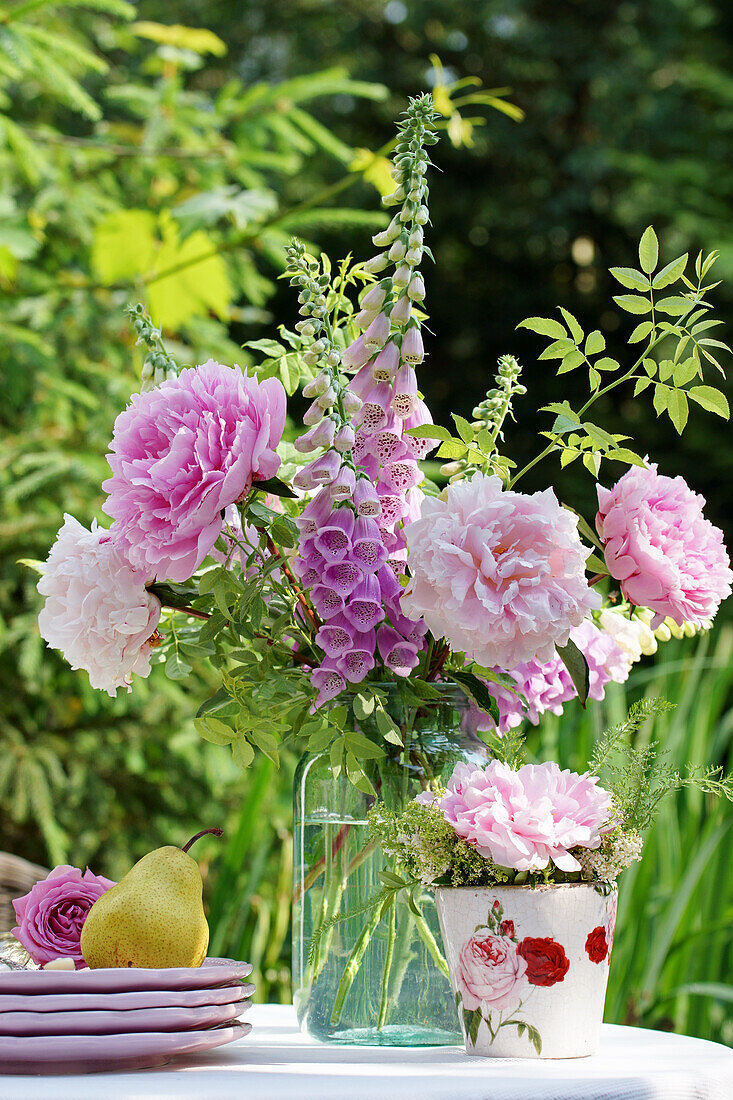 Blumenstrauß aus Pfingstrosen (Paeonia) und Fingerhut (Digitalis) auf Gartentisch