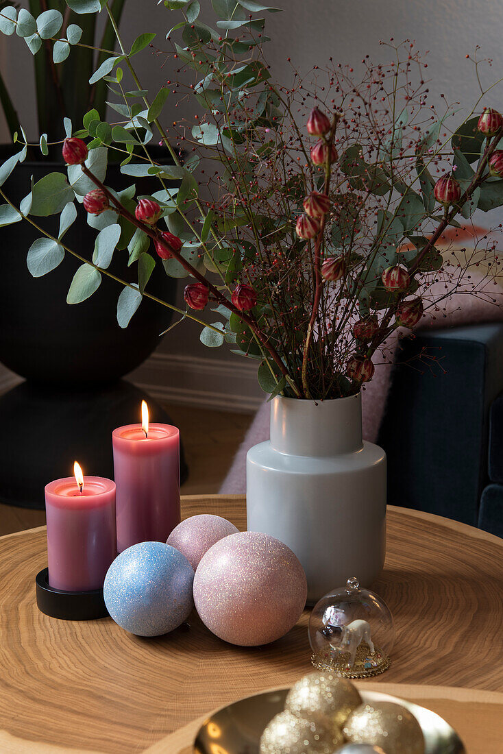 Weihnachtlich dekorierter Beistelltisch mit Eukalyptuszweigen, Kerzen und Kugeln