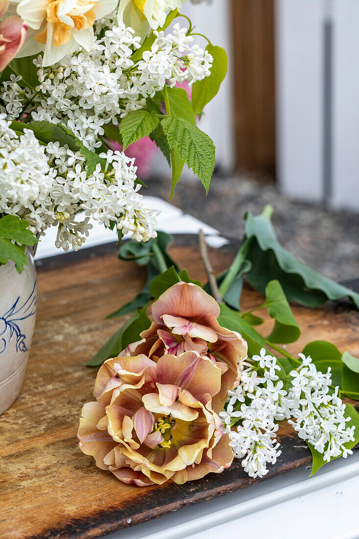 Blumenarrangement mit weißem Flieder und apricotfarbenen Tulpen