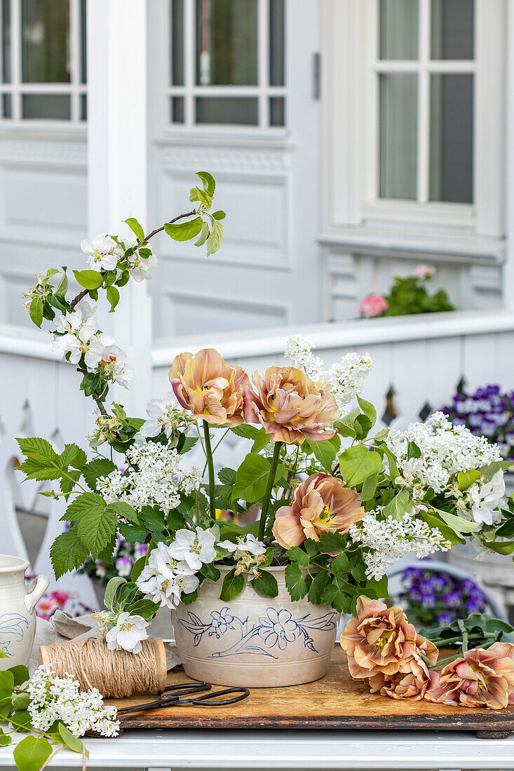 Lush spring bouquet of white lilac, apricot tulip and quince blossoms