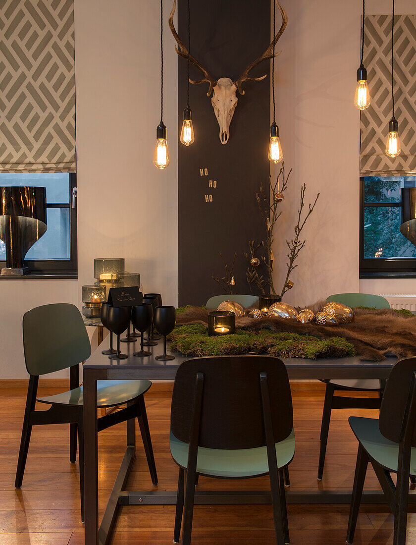 Dining table decorated with moss and Christmas ornaments, pendant light above it