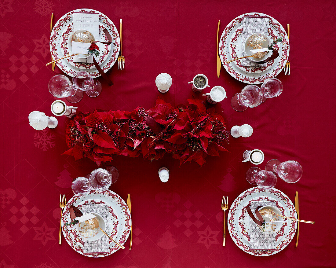 Christmas table setting with red tablecloth and garland of red poinsettia