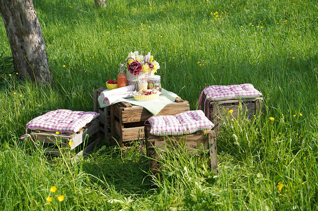 Picknickplatz aus Holzkisten mit Decke und Kissen im Garten