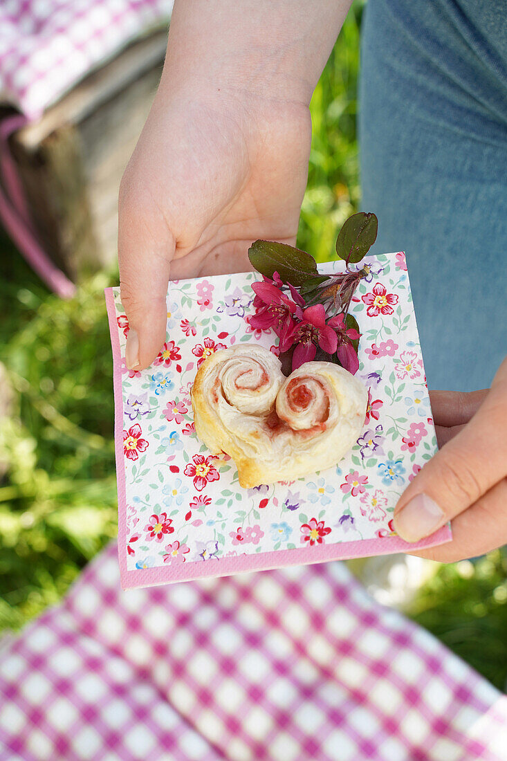 Puff pastry hearts filled with jam on a flowered napkin