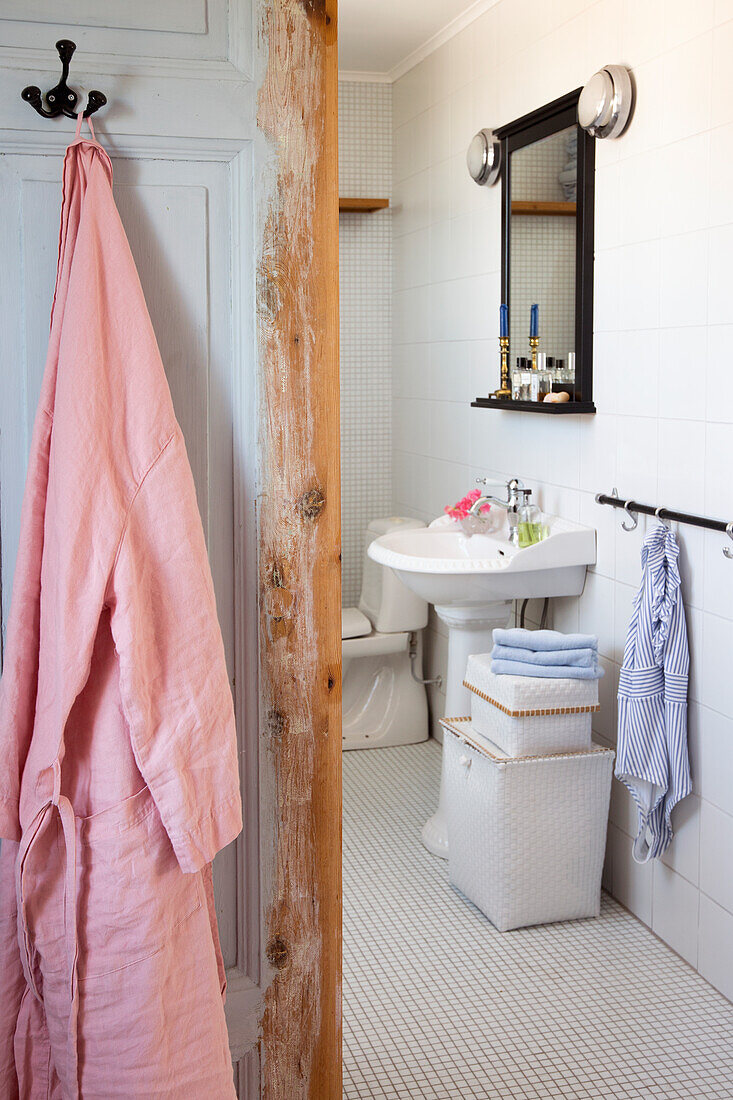 Weiß gefliestes Badezimmer, im Vordergrund Holztür
