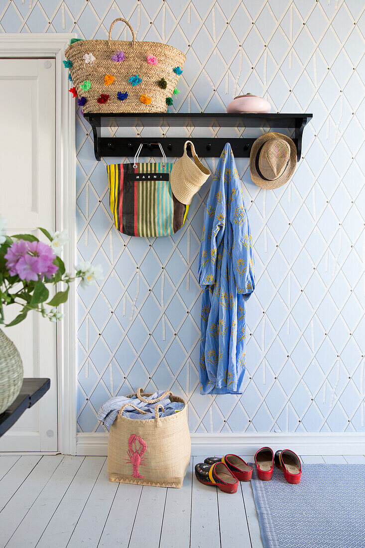 Wall mounted coat rack in the hallway with patterned light blue wallpaper