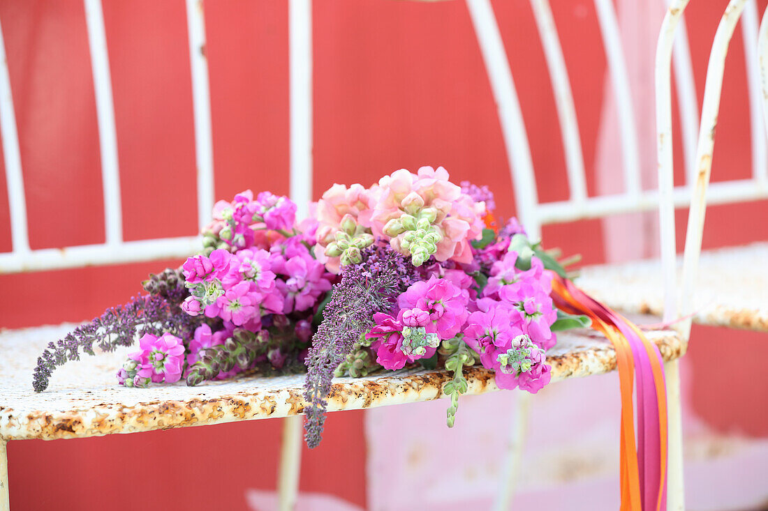 Colorful bouquet of snapdragons, butterfly bushes, and Stocks on rusty chair
