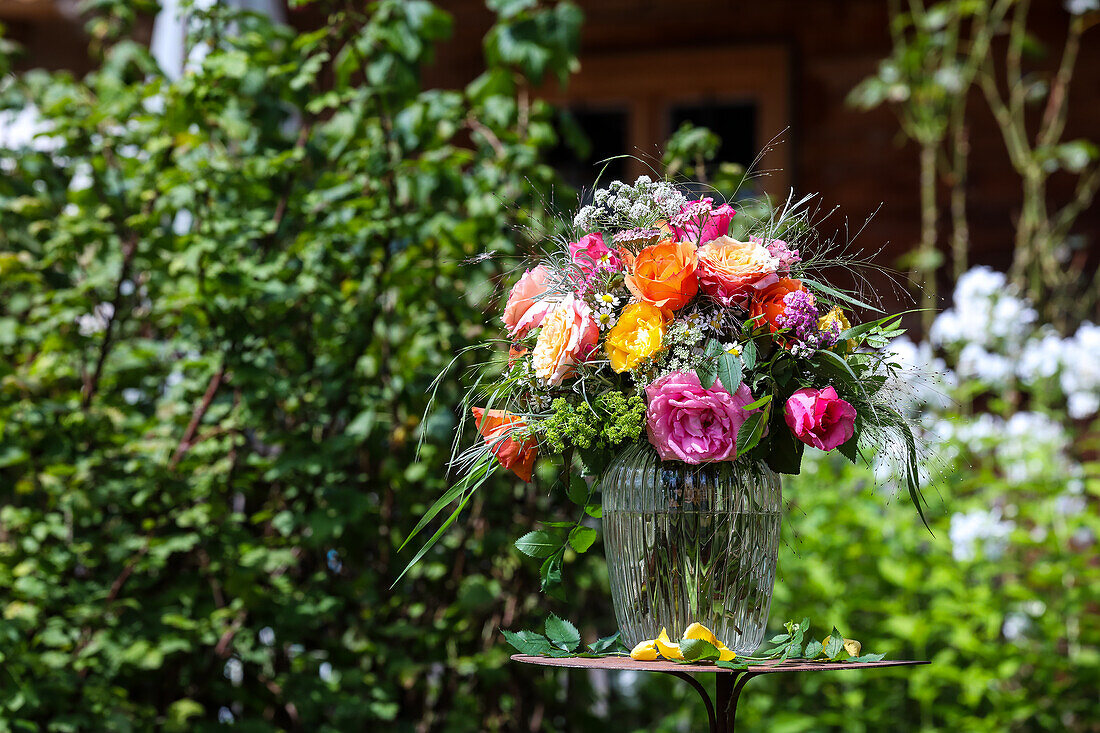 Bouquet of roses with camomile, grasses and lady's mantle in glass vase