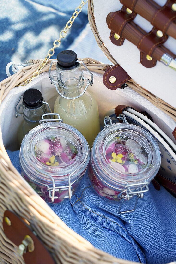 Picnic basket with preserving jars and drinks in glass bottles