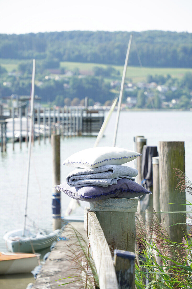 Pile of folded textiles on a jetty with a view of the lake