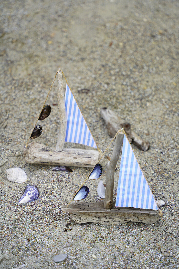 DIY-Segelboote aus Treibholz und Stoffresten am Sandstrand