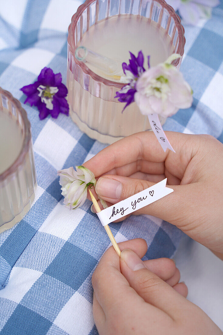 Flowery drink decoration with handwritten tags on a checkered cushion