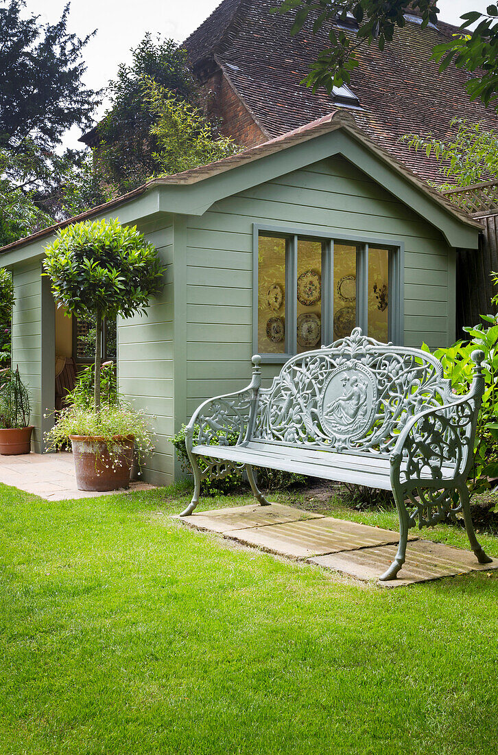 Ornate garden bench next to summer house