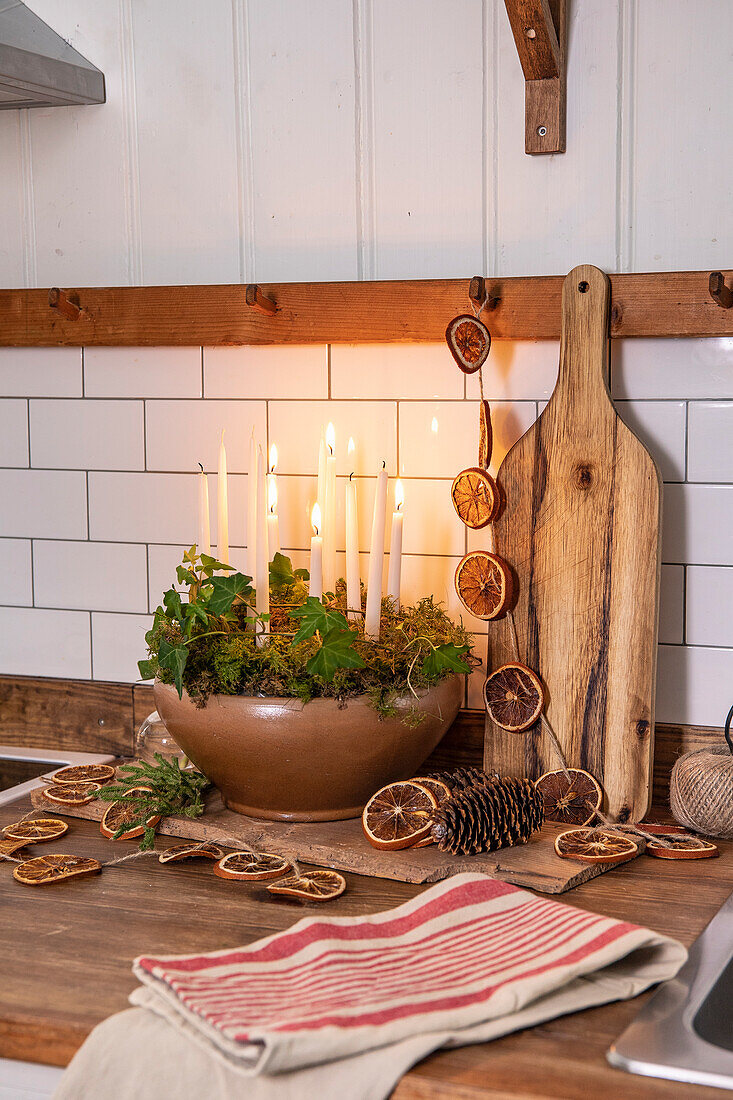 Advent arrangement with candles, ivy, moss and dried oranges in the kitchen